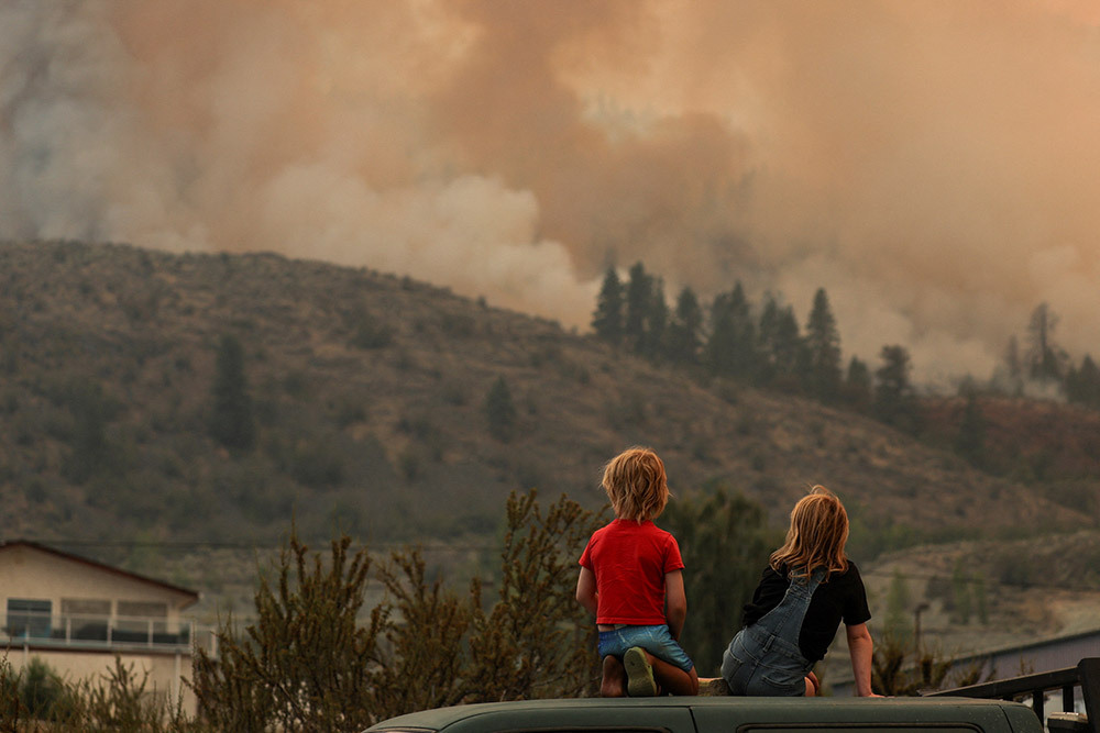 Locals gather to watch firefighting efforts amid heavy smoke from the Eagle Bluff wildfire, after it crossed the Canada-U.S. border and prompted evacuation of Osoyoos, Canada, July 30, 2023.