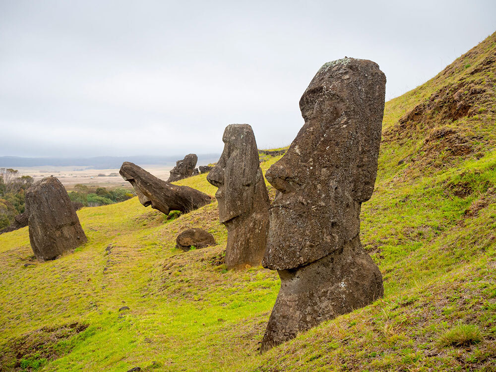 Large heads carved out of volcanic rock sit on a hillside