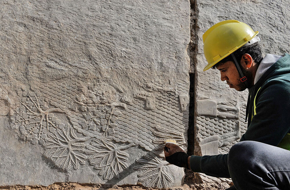 A man brushes an ornate relief carved into stone