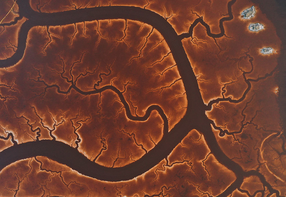 An aerial picture of a river snaking through a brown marshland