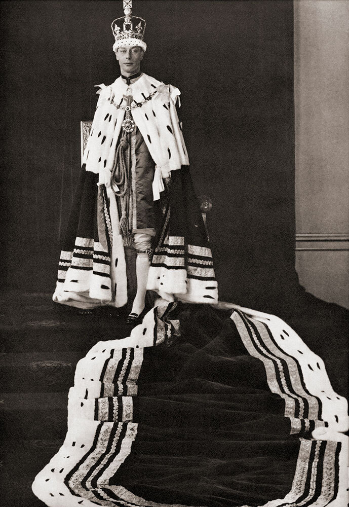 a black and white photo of King George VI wearing the Imperial State Crown and a robe