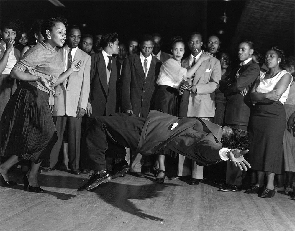 A picture of a man dancing, seemingly suspended in air a couple feet above and parallel to the ground.