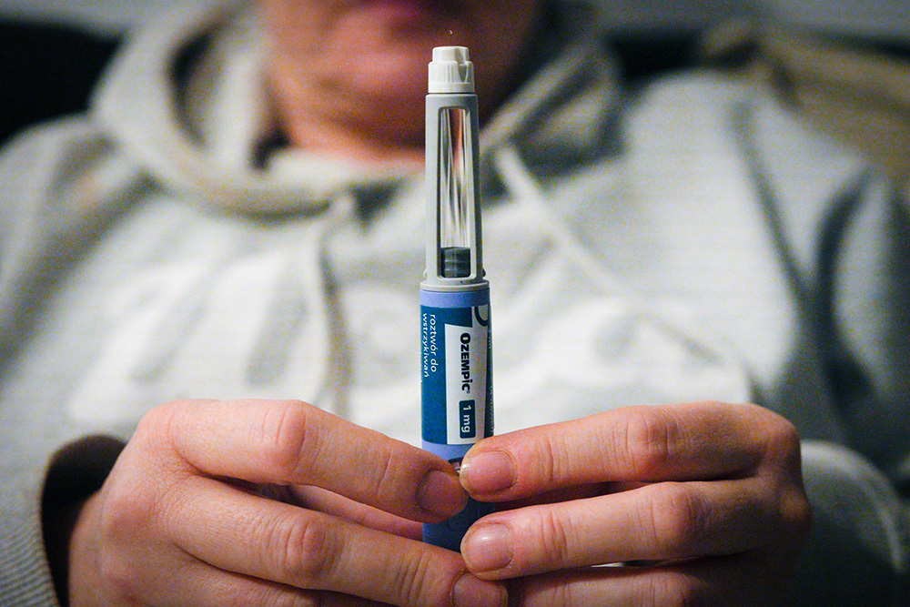 A close-up view of a woman's hands holding a multi-dose Ozempic syringe