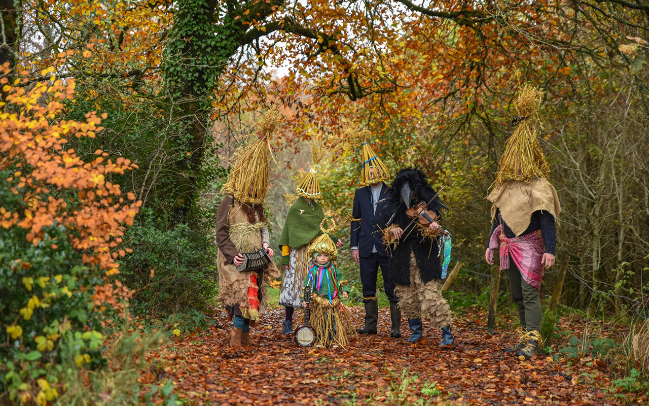 A family stands for a portrait in colorful mumming costumes.