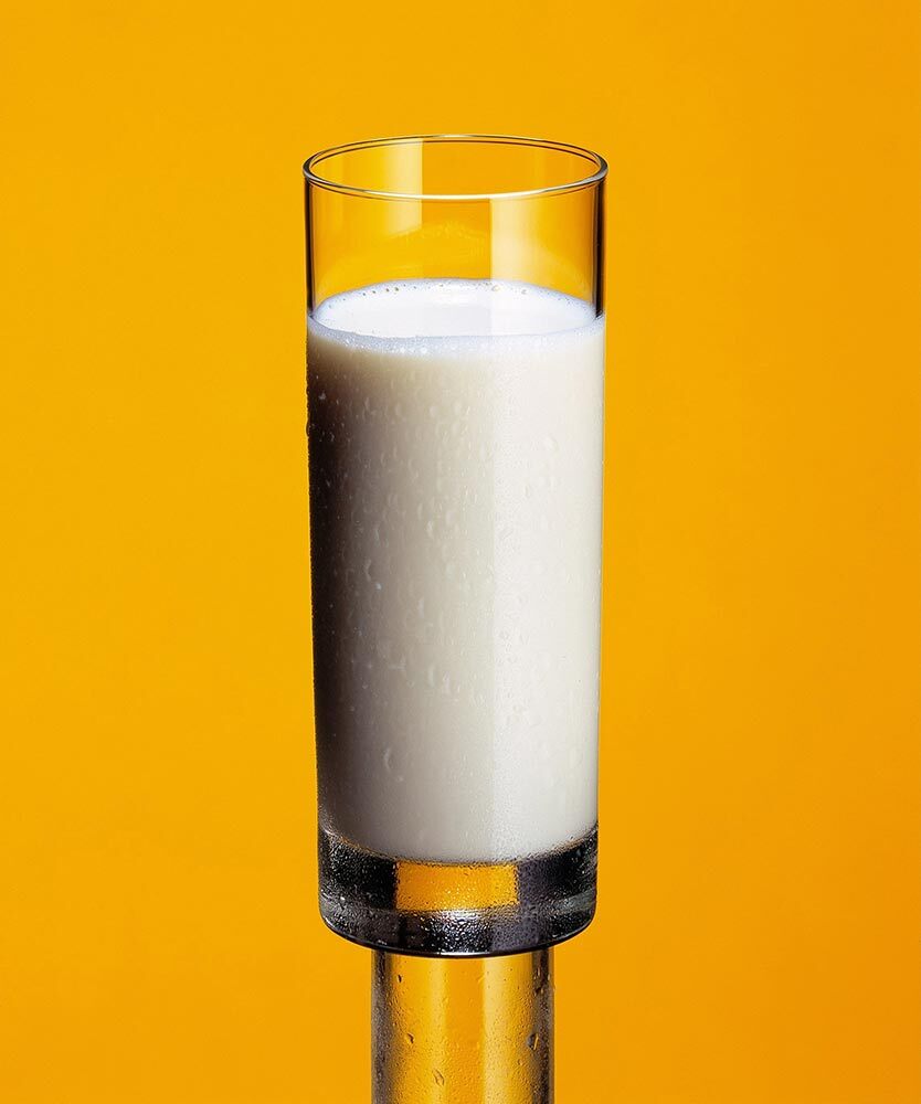 A glass of cold milk against a yellow background.