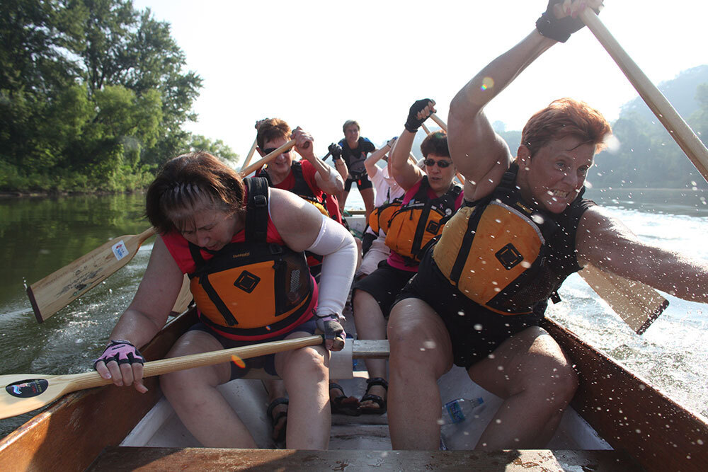 A boat full of women paddle a boat