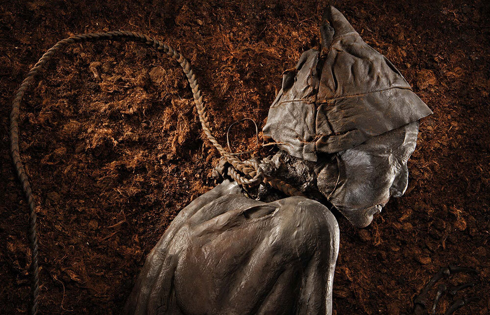 A woven leather cord, also preserved by the bog, winds around the neck of a preserved body known as Tollund Man