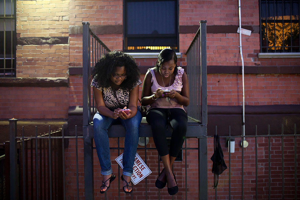 Young women check their phones on a fire escape on East 138th in the South Bronx. Often young women, and in particular young women of color, are the greatest innovators in the area of linguistics.