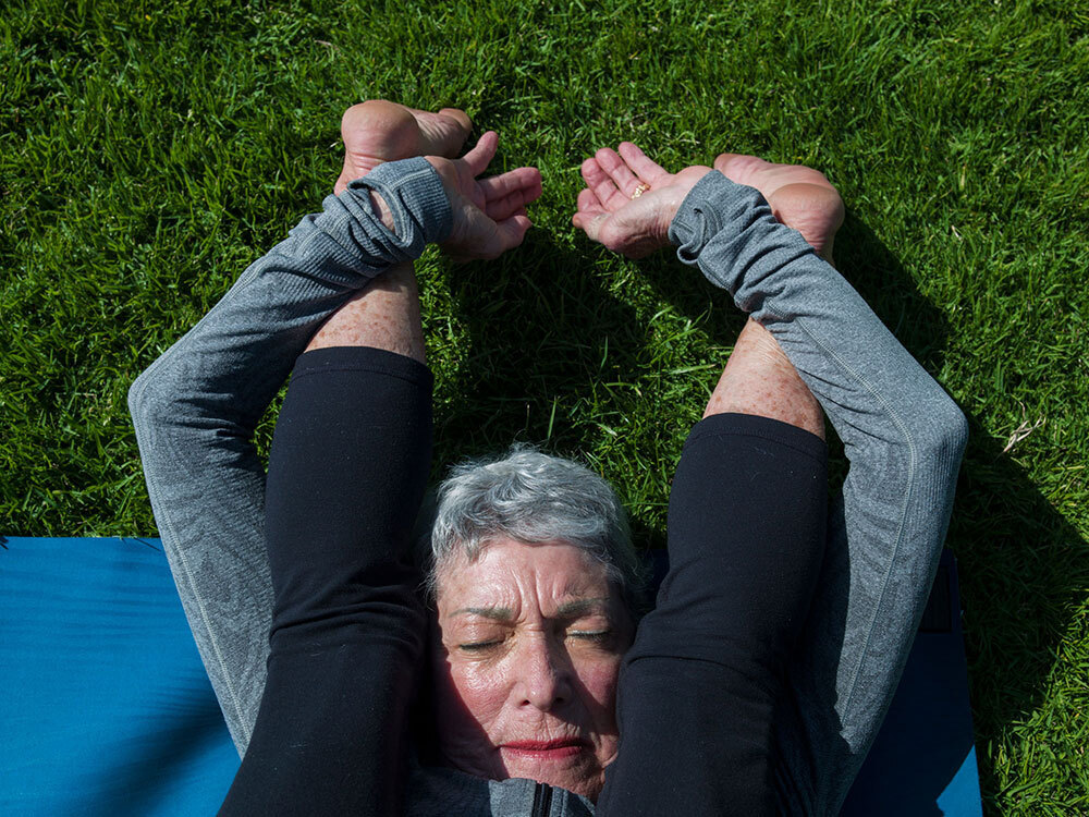 A picture of an older person stretching with their feet above their head