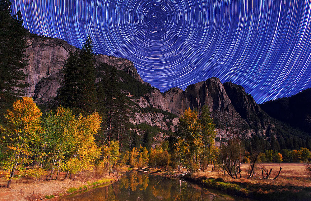 A long exposure photo of Yosemite with circular star trails in the background