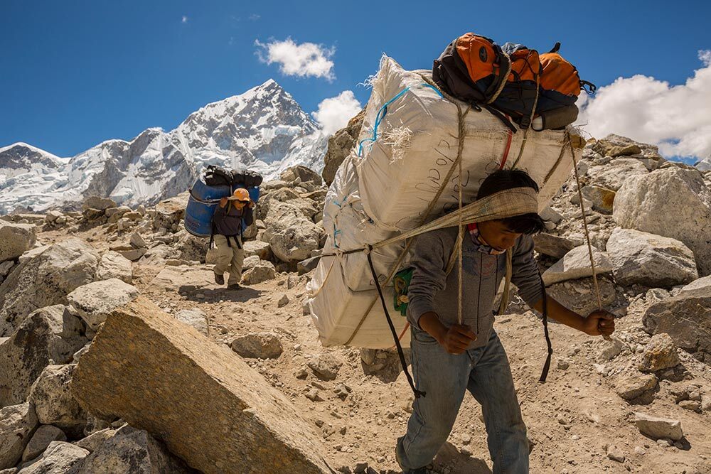 Porters carry loads back down from Base Camp to villages for storage in Gorak Shep, Nepal.