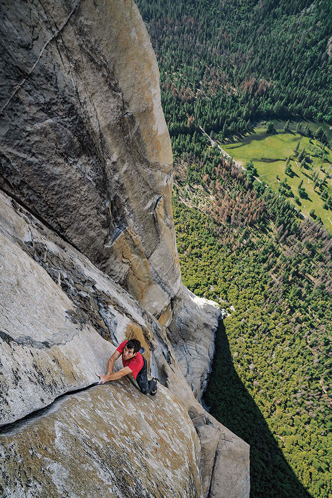 A man scales a stone cliff face with no ropes