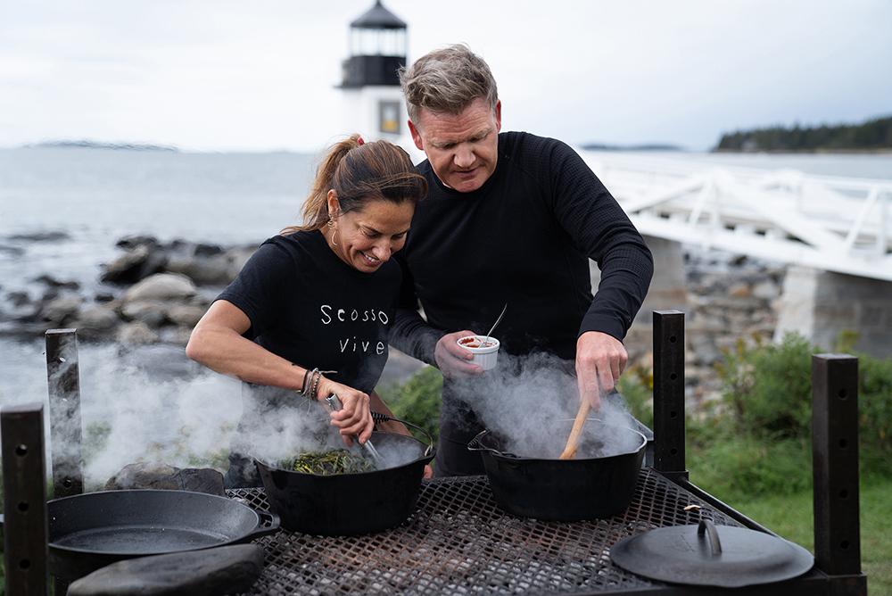 Chef Melissa Kelly (L) checks on her claims steaming under seaweed while Gordon Ramsay tends to his clam and lobster stew during the final cook in Rockland, Maine