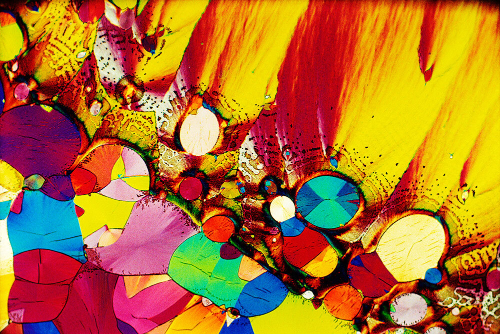 A rainbow of rounded colorful crystals amid a smearing of golden yellow and red