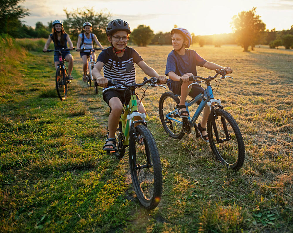 kids biking through a grassy field