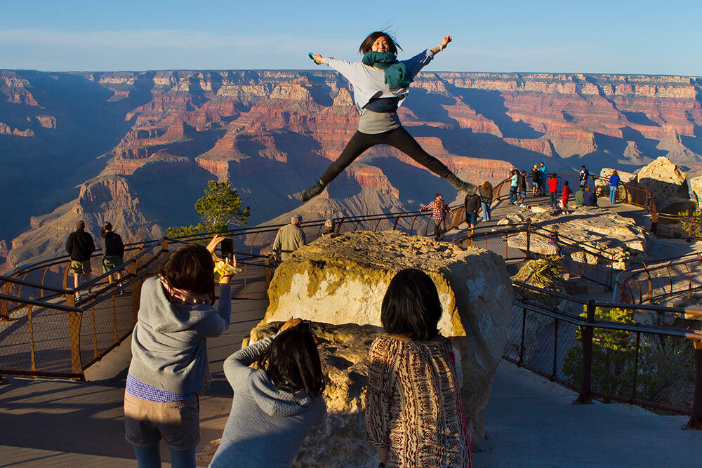 a woman jumps above the Grand Canyon at Mather Point