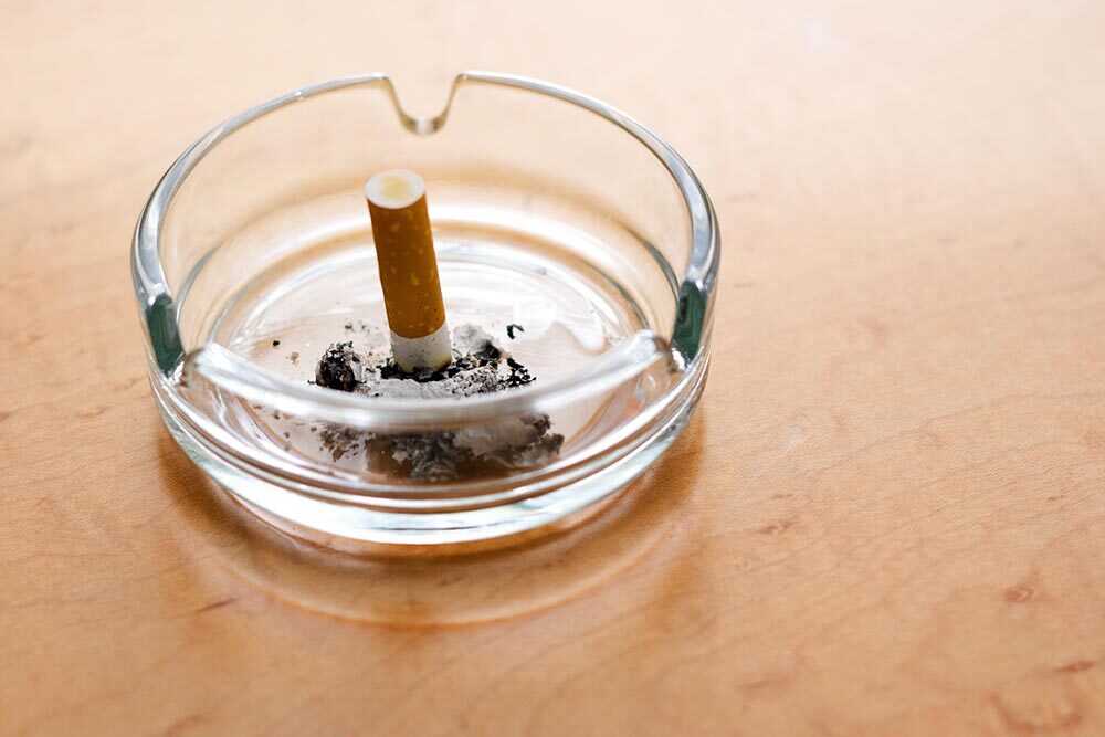 a cigarette butt in a glass ashtray