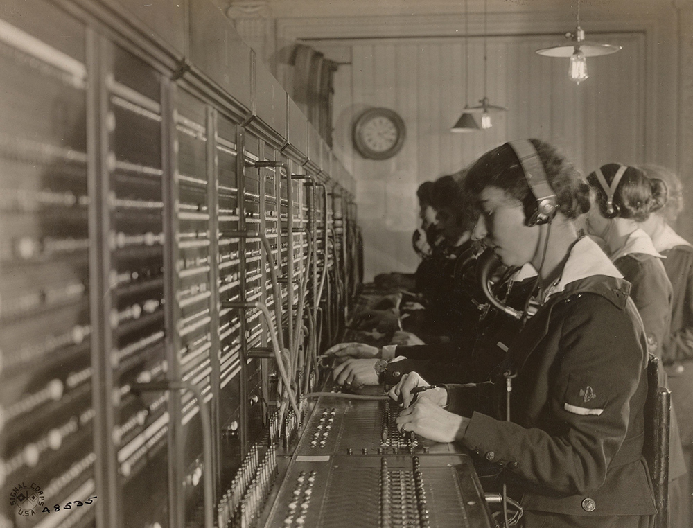 A black and white photo of a woman in the 1910s at a telephone exchange