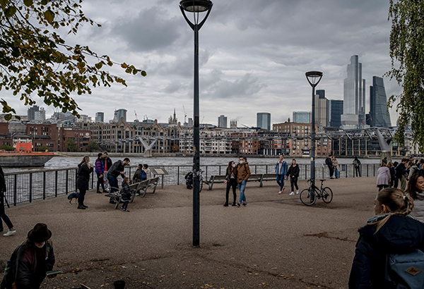 Pedestrians walk along the River Thames in London, October 18, 2020.