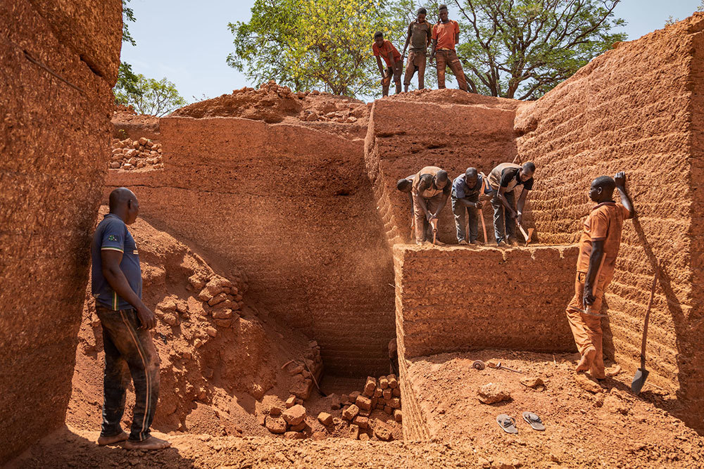 A photo of men hammering in a quarry of red rock