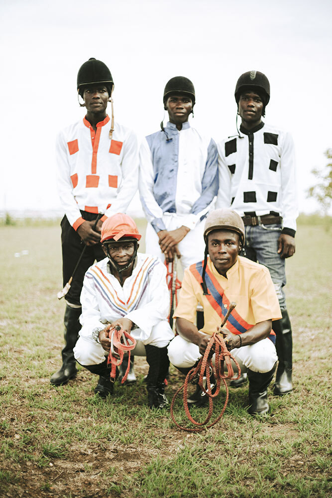 Five men in jockey jerseys pose for the camera