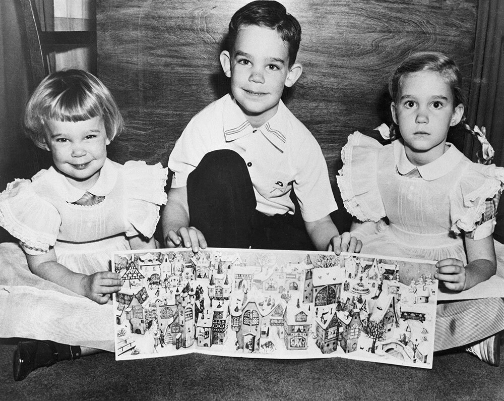 A black and white photo of kids holding a tri-fold card