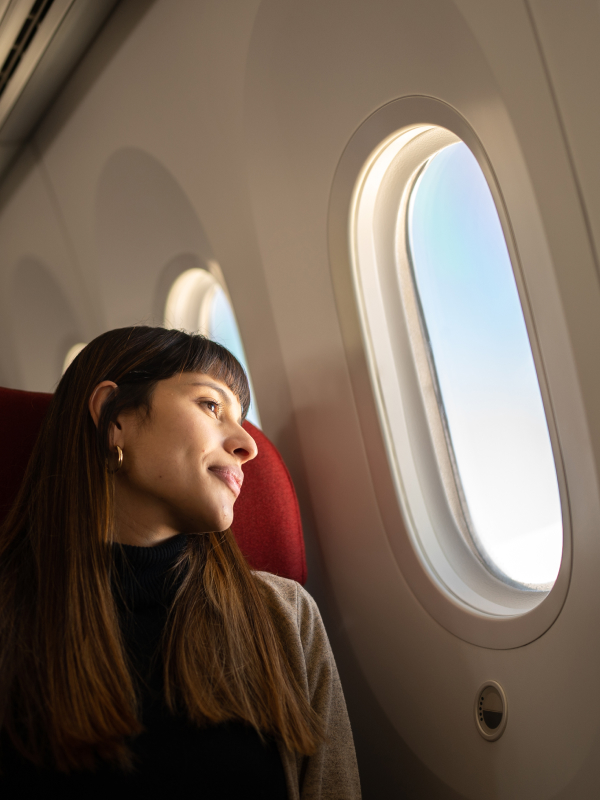A passenger looking outside an airplane window.