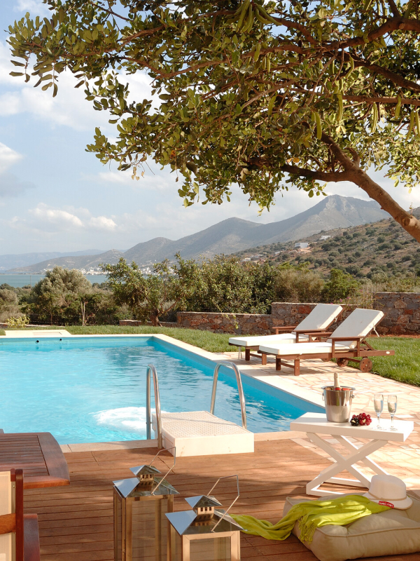 A deck and swimming pool at a hotel high up in the hillside with a view of a nearby mountain.