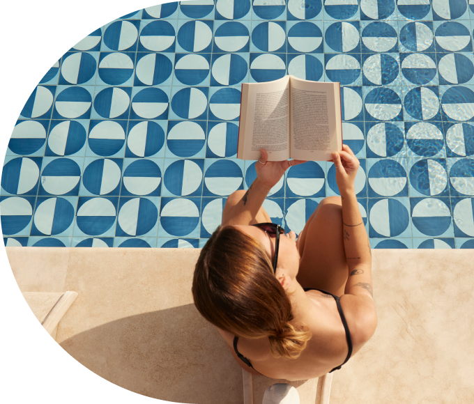 A guest reading a book while sitting on the edge of a hotel pool.