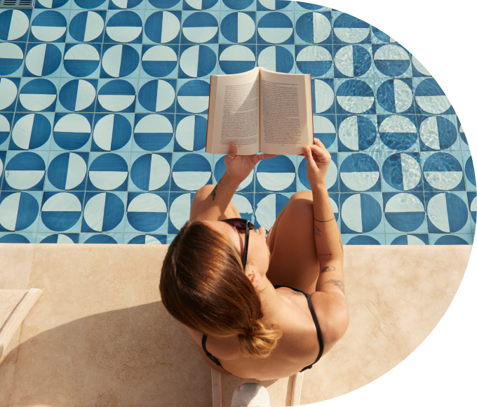 A guest reading a book while sitting on the edge of a hotel pool.