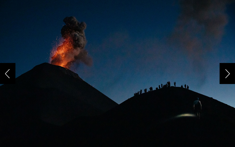 Hikers (right) are pictured getting a close-up view of the erupting Volcán de Fuego in Guatemala (left) at night. 