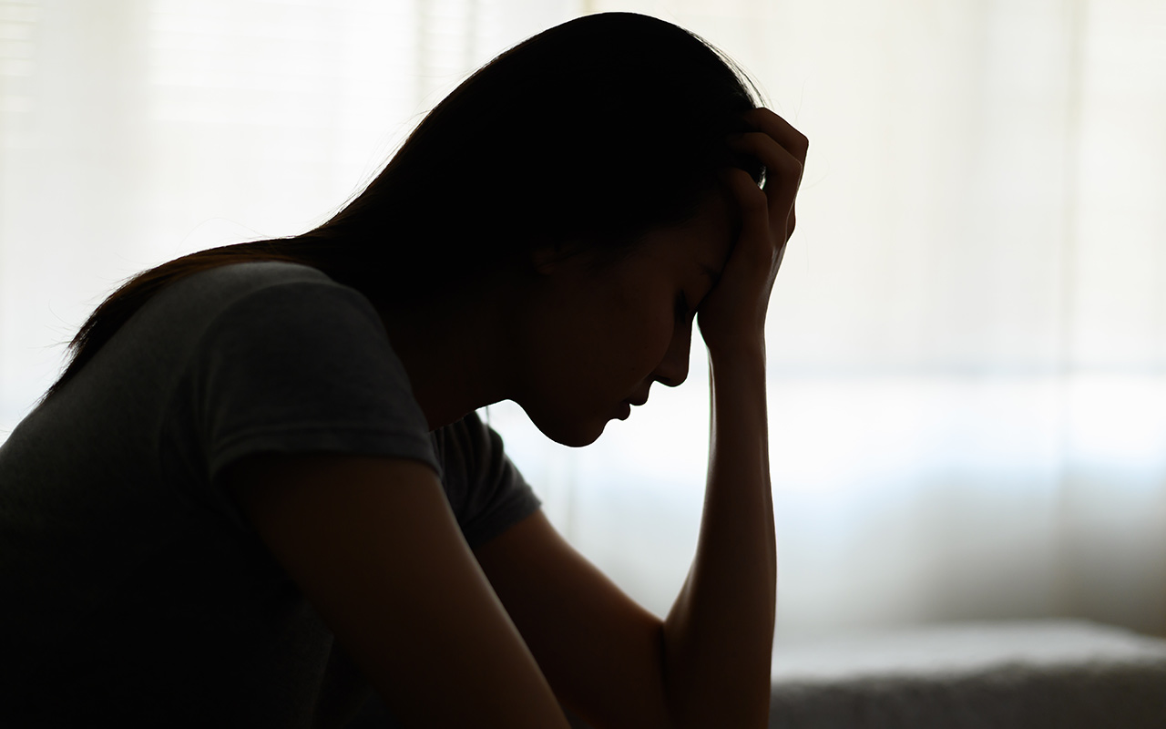  A silhouette of a person holding their head in their hands.