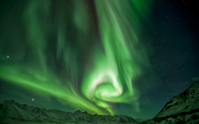 The northern lights dance over snow-covered mountains in Yukon Territory