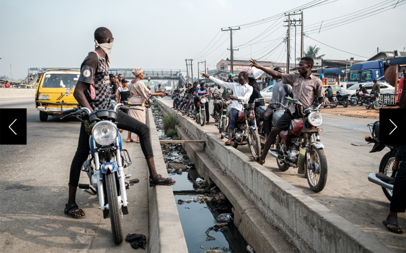 Along the median of one of Lagos’s major expressways, okada riders beckon to potential passengers.