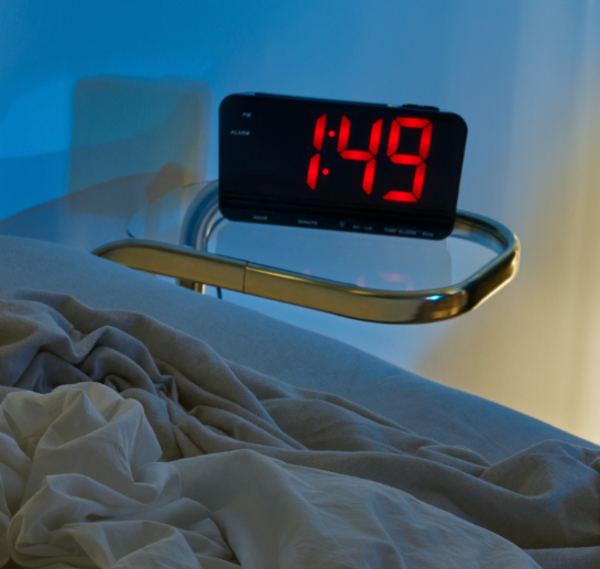 An alarm clock by a bed.