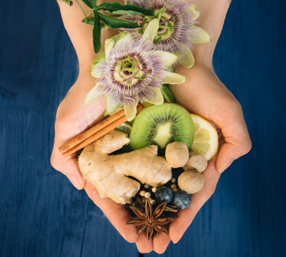 Fruits, plants, and other remedies rest in someone’s hands.