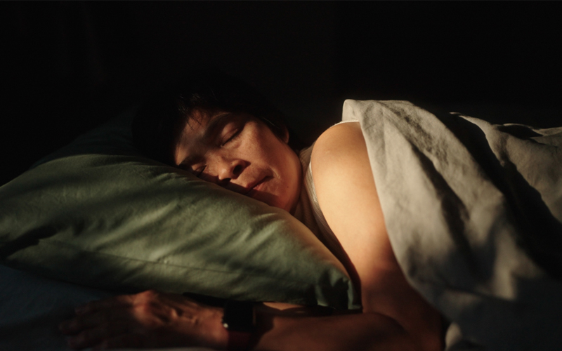 A man sleeps on his side in bed. 