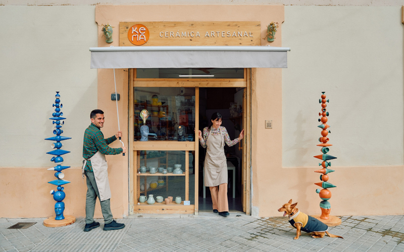 A woman stands smiling in the doorway of a ceramics store. 