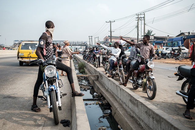 Along the median of one of Lagos’s major expressways, okada riders beckon to potential passengers.