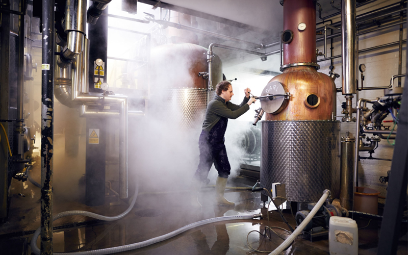 A man works a machine to distill gin. 