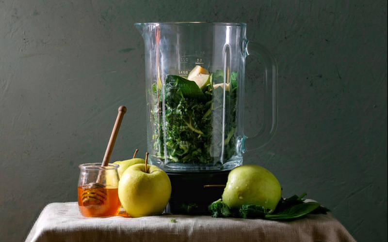 Kale and apples are pictured inside a blender.