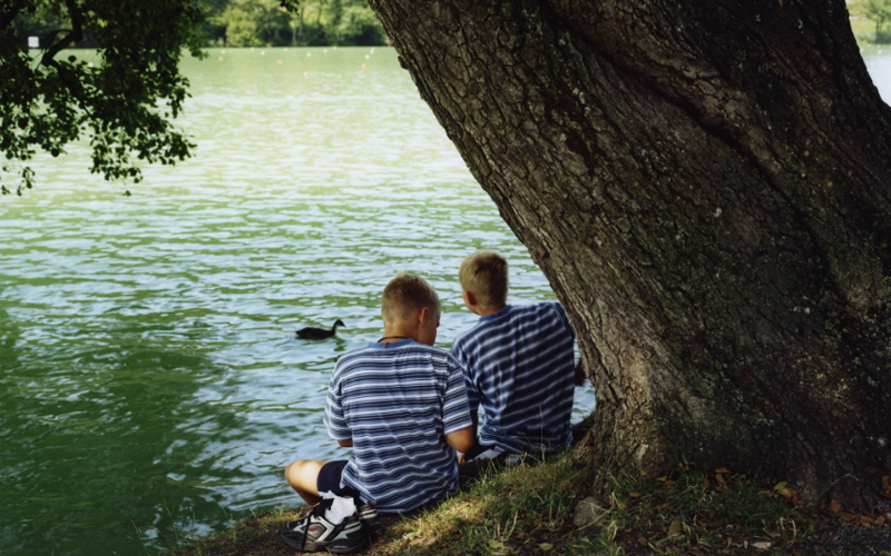 Twins sit near Lake Geneva in Lausanne, Switzerland.