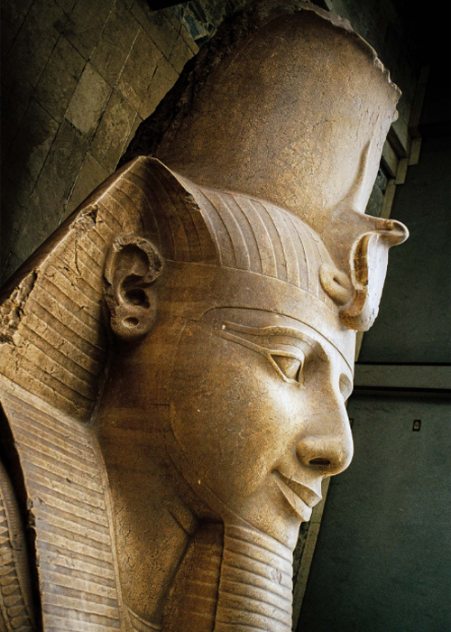 The head of Ramses II’s recumbent colossus at Memphis wears the nemes, or striped head cloth, and the royal uraeus serpent of divinity and authority.