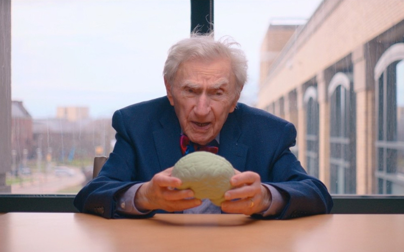 Neurologist Howard Tucker, who is 102 years old, holds a model of a brain. 