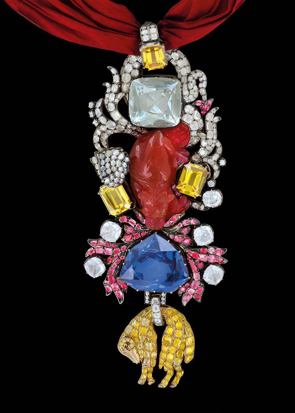 A replica of Louis XV’s Order of the Golden Fleece. It features a white gem stacked over a red carved lion, flanked by yellow gems, stacked onto a blue diamond on top of a lamb encrusted with yellow gems. 