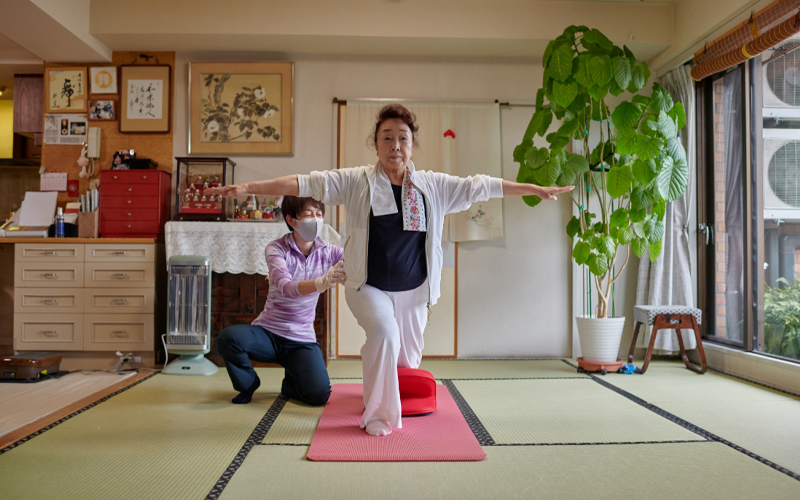 A middle-aged Japanese woman balancing as she does a lunge exercise.