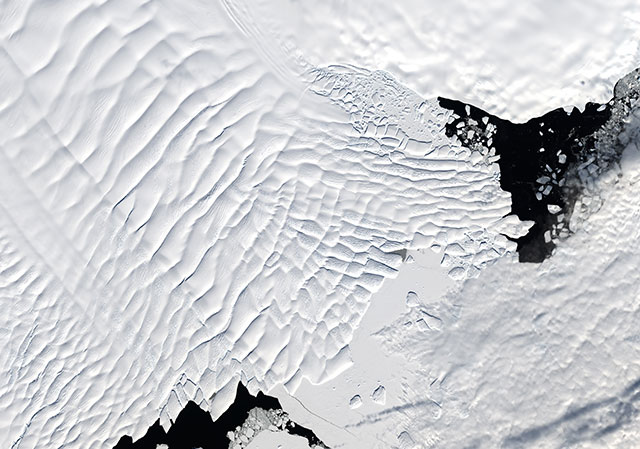 An overhead photo of Totten Glacier oozing off the Antarctic coast and floating on the ocean.