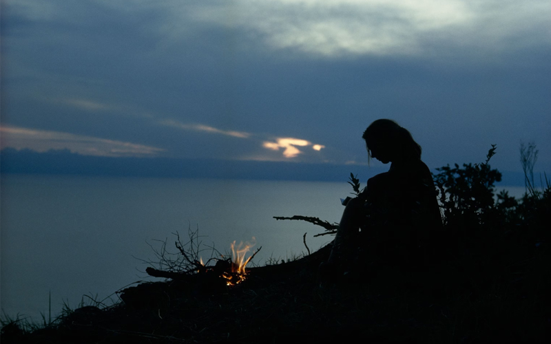 The sun's fading glow on Lake Tanganyika silhouettes the author, who is preparing for a lonely, nightlong vigil among the cimpanzees.
