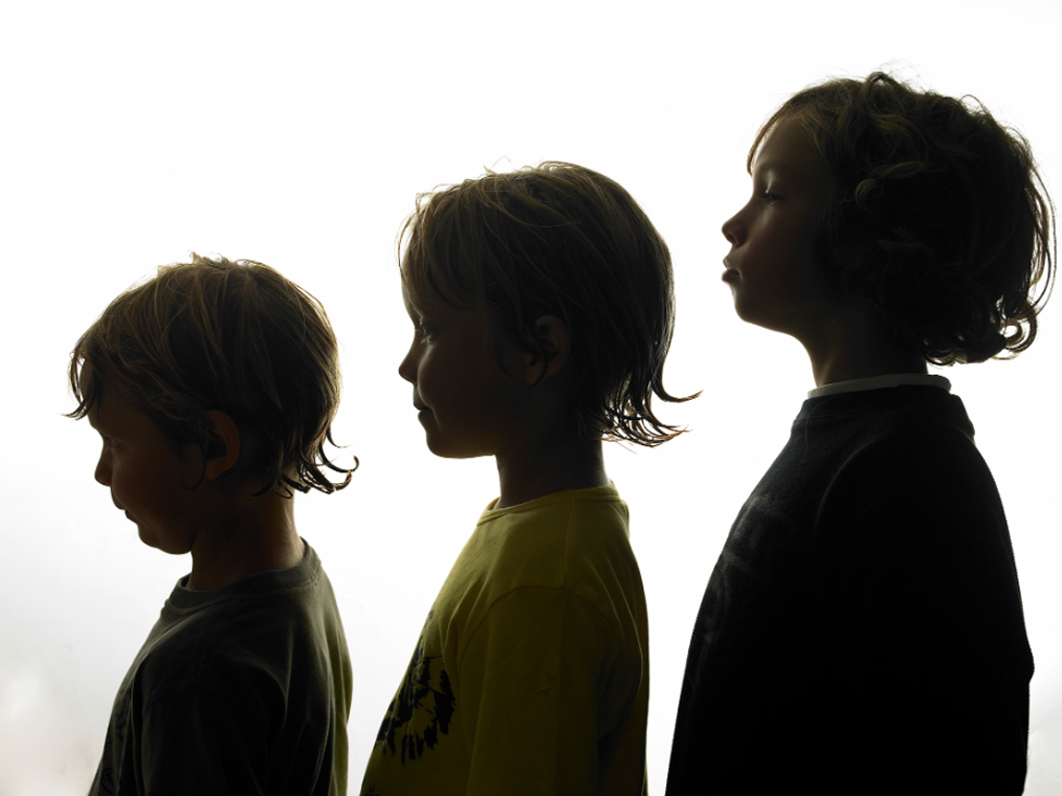 Three boys ages five to eight stand in a line.