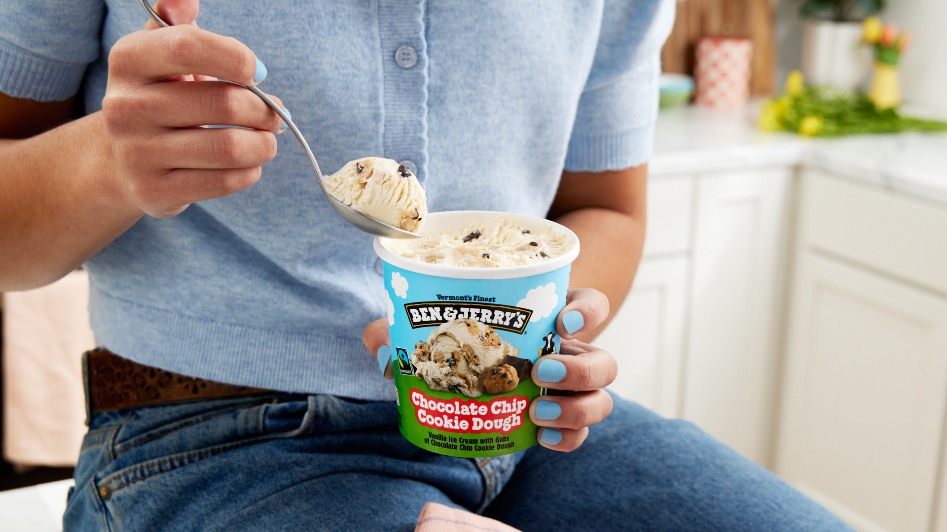 Person in kitchen holding a pint of Ben & Jerry's Chocolate Chip Cookie Dough ice cream.